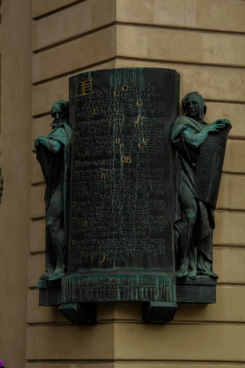 Una targa commemorativa in bronzo montata sull'angolo di un edificio in pietra.